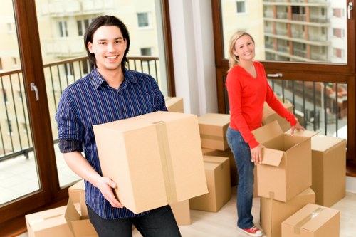 Professional movers carrying household furniture through a local property entrance